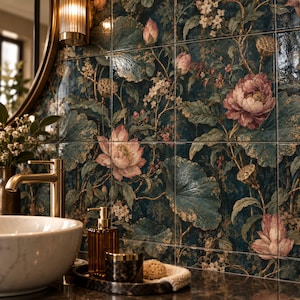 May include: A wall of square ceramic tiles featuring a dark teal background with a botanical pattern of pink lotus flowers, green lily pads, and small white blossoms. A gold faucet, a white marble basin, and a soap dispenser are in the foreground.