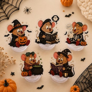 Könnte beinhalten: Fünf durchsichtige Acryl-Handyhalterungen mit Cartoon-Mäusen in Halloween-Kostümen. Eine Maus hält einen Kürbis, eine liest ein Zauberbuch, eine trägt ein Skelettkostüm, eine rührt in einem Kessel und eine liest einen Hexenratgeber mit einer schwarzen Katze.
