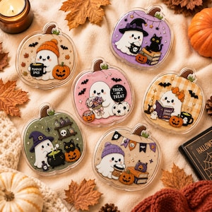May include: Six clear acrylic charms shaped like pumpkins, each featuring a cute ghost character. Designs include ghosts with pumpkin spice, a black cat, a bouquet, a book titled Spooky Stories, a cauldron, and a banner with autumn leaves.