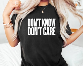May include: A black short-sleeved t-shirt featuring the white text DON'T KNOW DON'T CARE printed in a bold, sans-serif font across the chest. The garment has a classic crew neckline and a relaxed fit, providing a simple and direct graphic design.