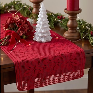 Puede incluir: Un camino de mesa rectangular de ganchillo rojo con un patrón repetitivo de copos de nieve. El camino está elaborado con un diseño calado tipo rejilla y acabado con un borde recto y limpio, proporcionando una superficie texturizada.
