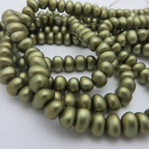 May include: A strand of olive green glass beads. The beads are round and have a smooth, matte finish.