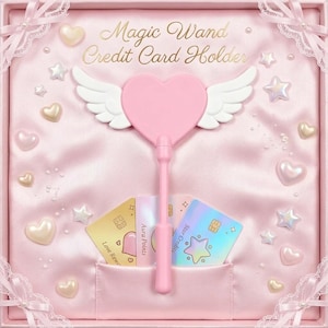 Può includere: Un porta carte di credito rosa a forma di cuore con ali bianche, presentato in una scatola foderata in raso. La scatola riporta la scritta Magic Wand Credit Card Holder e include tre carte etichettate Love Rewards, Aura Points e Star Credits.