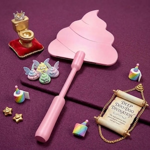 Könnte beinhalten: Ein rosa Handspiegel in Kackhaufenform, eine goldene Toilettenfigur mit Krone auf rotem Kissen, drei kleine geflügelte Kackhaufen-Figuren, zwei regenbogenfarbene Partyhut-Rollen, zwei goldene Sternanhänger und eine Schriftrolle mit Text.