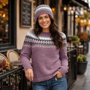 May include: A purple knit jumper and matching beanie featuring a fair isle pattern across the chest and crown. The design incorporates horizontal bands of white, light blue, and dark purple geometric shapes on a solid purple textured knit base.