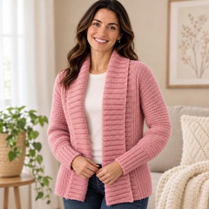 May include: A dusty rose open-front cardigan featuring a wide ribbed shawl collar and matching ribbed cuffs. The knit garment has long sleeves and a textured stitch pattern throughout, worn over a plain white shirt and blue denim jeans.