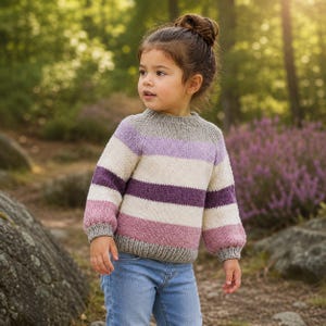 May include: A long-sleeve knit sweater featuring horizontal stripes in shades of light purple, cream, dark purple, and dusty pink. The sweater has a ribbed crew neckline, ribbed cuffs, and a ribbed hem, all in a solid light gray yarn color.
