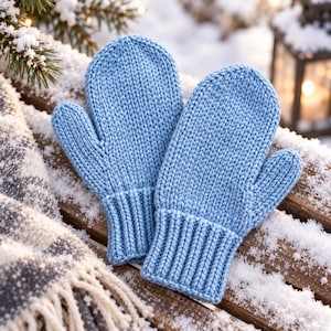 May include: A pair of light blue knitted mittens featuring a classic stockinette stitch pattern on the main body and a ribbed cuff at the wrist. The mittens are constructed with a separate thumb section and have a consistent, uniform texture.