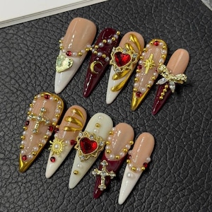 Gotische barok rode hart-kruis nepnagels, luxe lange stiletto nepnagels, handgemaakte nagels met robijnrode strass steentjes, parels en gouden bedeltjes, donker koket