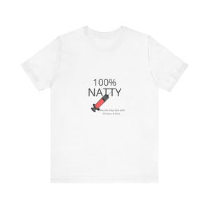 Op de afbeelding: Een wit t-shirt met korte mouwen en de zwarte tekst 100% NATTY boven een afbeelding van een injectiespuit met rode vloeistof. Onder de spuit staat de tekst Results may vary with Chicken & Rice in een klein zwart lettertype op de borst.