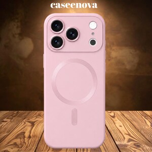 Puede incluir: Una funda para smartphone de color rosa claro con acabado mate, que presenta un anillo de carga magnético circular en la parte posterior, un recorte para triple cámara y un módulo de flash. El texto caseenova está impreso en blanco arriba.