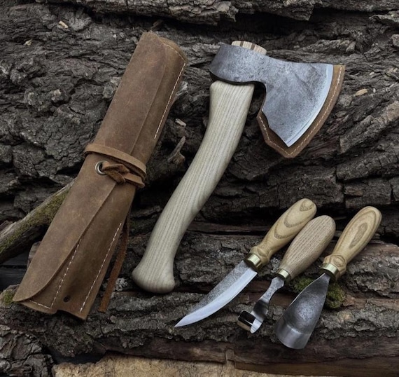 A blacksmith actually hammered these four carving axes into shape — the leather roll presentation makes this feel like an artifact, not a product.
