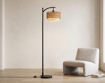 May include: A tall black metal floor lamp with a curved arm and a cylindrical shade. The shade features an outer layer of woven tan material and an inner white fabric diffuser. The lamp has a round base and a black power cord with a floor switch.