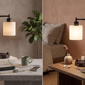 May include: A black metal desk lamp with a cylindrical fabric shade and a circular base featuring integrated power outlets, a USB port, and a rotary dimmer switch. The lamp emits a warm glow and includes a power cord extending from the base.