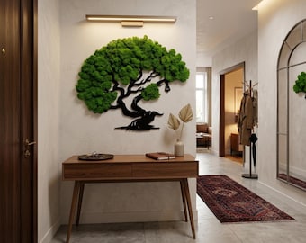 May include: A wall-mounted art piece featuring a black silhouette of a tree with vibrant green preserved moss foliage. The tree is positioned above a wooden console table with two drawers, which holds a small tray, a notebook, and a vase.