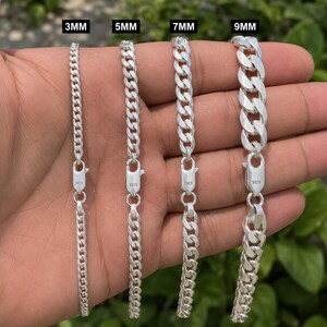 Puede incluir: Cuatro pulseras de cadena tipo barbada de plata con cierres de langosta, cada una marcada con S925. Las cadenas se muestran en anchos variables etiquetados como 3mm, 5mm, 7mm y 9mm, con un acabado metálico pulido y eslabones planos entrelazados.