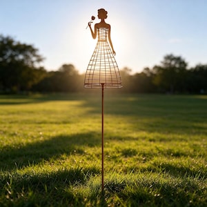 Può includere: Un picchetto da giardino in metallo con la sagoma di una figura che tiene in mano un fiore. La figura presenta una struttura della gonna in filo metallico ed è montata su un'asta di metallo sottile e dritta da inserire nel terreno.