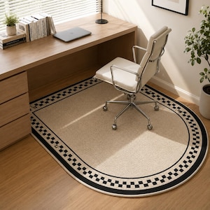 May include: An oval-shaped area rug featuring a solid beige center and a wide black and white checkered border. The rug is positioned on a light wood floor beneath a desk and a white office chair, providing a defined space for the workspace area.