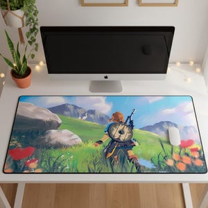 May include: A rectangular desk mat featuring a vibrant, illustrated landscape scene. The artwork depicts a character viewed from behind, carrying a round shield and sword, walking through a grassy field with mountains, blue sky, and clouds.