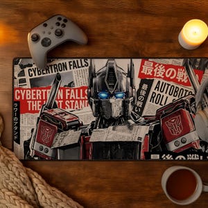 Può includere: Un tappetino da scrivania rettangolare con un'illustrazione grafica di una testa di robot con occhi blu luminosi, sovrapposta a uno sfondo di ritagli di giornale con il testo Cybertron Falls, The Last Stand e Autobots Roll Out in rosso e nero.