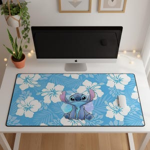 Peut inclure: Un tapis de bureau rectangulaire avec un fond bleu clair orné d'un motif répétitif de fleurs d'hibiscus blanches et de feuilles de palmier. Au centre, une illustration graphique du personnage extraterrestre bleu Stitch assis.
