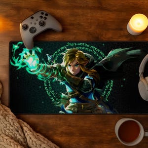 May include: A rectangular desk mat featuring a graphic illustration of a blonde character with a glowing green arm and magical energy rings. The mat has a black background with a dark maze-like pattern and is positioned on a wooden surface.