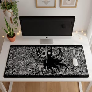 Puede incluir: Una alfombrilla de escritorio rectangular con una ilustración detallada en blanco y negro del personaje Hollow Knight rodeado por un denso collage de varias criaturas y patrones del juego, con un ratón de ordenador blanco a la derecha.