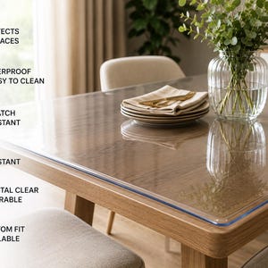 May include: A clear, transparent protective table cover resting on a wooden dining table. The image includes text labels: PROTECTS SURFACES, WATERPROOF & EASY TO CLEAN, SCRATCH RESISTANT, HEAT RESISTANT, CRYSTAL CLEAR & DURABLE, and CUSTOM FIT AVAILABLE.