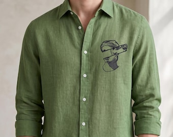 May include: A long-sleeved olive green button-down shirt featuring a black embroidered graphic of a classical statue head split into two horizontal sections on the left chest. The shirt has a standard collar and white buttons.