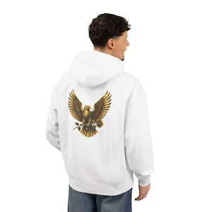 Op de afbeelding: Een witte hoodie met een afbeelding op de achterkant van een gouden adelaar met gespreide vleugels, die een enkele roos in zijn klauwen houdt. De hoodie heeft lange mouwen, een capuchon met trekkoord en geribbelde boorden bij de mouwen en zoom.