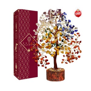 Könnte beinhalten: Eine dekorative Baumskulptur mit Ästen aus goldfarbenem Draht, die mit bunten Edelstein-Chips in Rot, Gelb, Grün, Transparent und Blau verziert sind. Der Baum hat einen braunen Stamm und steht auf einem runden Sockel neben einer hohen bordeauxroten Schachtel.