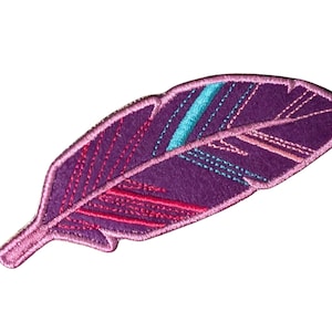 Op de afbeelding: Een geborduurde verenpatch met een dieppaarse basis en een lichtroze gestikte rand. Het ontwerp bevat diagonale accentlijnen in fel turquoise, magenta en zachtroze draad, wat zorgt voor een gestructureerd en kleurrijk uiterlijk.