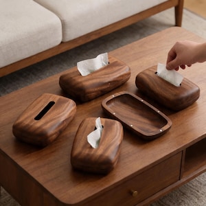 Peut inclure: Un ensemble de boîtes à mouchoirs en bois brun foncé aux bords arrondis et à la finition lisse. Trois des boîtiers rectangulaires présentent une fente centrale pour distribuer les mouchoirs, tandis qu'un plateau ouvert comporte des détails métalliques.