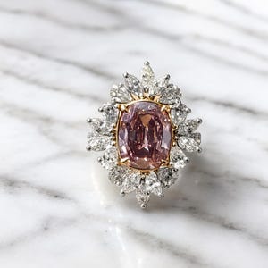 Könnte beinhalten: Ein Ring mit einem großen, oval geschliffenen rosa Mittelstein in einer Gelbgoldfassung, umgeben von einem Kranz aus zahlreichen weiß geschliffenen Diamanten in Marquise- und Tropfenform in Weißmetall, in einem blütenartigen Design.