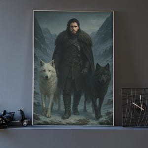 K&ouml;nnte beinhalten: Ein gerahmter vertikaler Wandkunstdruck, der eine dunkelhaarige Person in einem schweren schwarzen Mantel mit Pelzkragen in einem verschneiten Gebirgspass zeigt. Ein gro&szlig;er wei&szlig;er Wolf steht links und ein gro&szlig;er schwarzer Wolf rechts daneben.