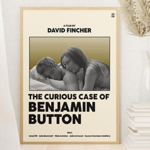 May include: A framed movie poster for The Curious Case of Benjamin Button with a cream background and black text. The poster features a black and white photograph of two people lying in bed, the text A FILM BY DAVID FINCHER, and the cast names.