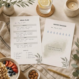 Puede incluir: Dos hojas de papel blancas con un plan de comidas y un rastreador de agua. El plan de comidas enumera desayuno, almuerzo, cena, bocadillos y una lista de compras con texto escrito a mano. El rastreador de agua incluye ocho iconos de gotas de agua azules y el texto, Small steps every day lead to big results, con un acento de acuarela verde e ilustraciones de hojas.