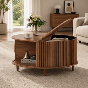 May include: A round wooden coffee table with a slatted exterior design and a hinged top that opens to reveal interior storage. The table features an open side shelf containing a book titled Alvar Aalto, a small vase, and a bowl.