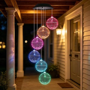 Pode incluir: Uma luminária suspensa movida a energia solar com seis bolas de discoteca esféricas dispostas em cascata vertical. Cada esfera é coberta por pequenos azulejos quadrados reflexivos e brilha em uma cor diferente, incluindo vermelho, laranja, roxo, azul, turquesa e verde.