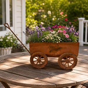 Puede incluir: Una jardinera con forma de carro de metal marrón desgastado, con un mango largo y cuatro ruedas de radios. El recipiente rectangular está lleno de un arreglo floral de lavanda morada, pequeñas margaritas blancas y flores de color rosa.