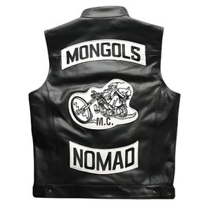 Puede incluir: Un chaleco de cuero negro con parches blancos en la espalda. El parche superior dice MONGOLS en letras negras. El parche central muestra una figura de dibujos animados en una motocicleta con el texto M.C. debajo. El parche inferior dice NOMAD.