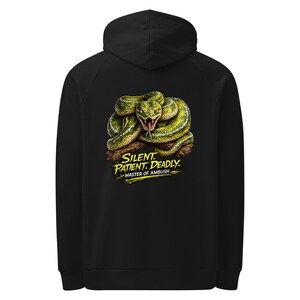 May include: A black hooded sweatshirt featuring a graphic on the back of a coiled green snake with an open mouth and fangs. Below the snake, the yellow text reads: SILENT. PATIENT. DEADLY. MASTER OF AMBUSH. The hoodie has long sleeves and a hood.