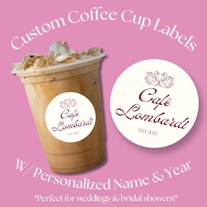 May include: A clear plastic cup filled with iced coffee featuring a round white label with the text Café Lombardi and EST 2027, accompanied by a separate matching circular label. The text Custom Coffee Cup Labels W/ Personalized Name & Year appears.