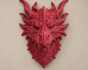 Può includere: Una scultura da parete a forma di testa di drago rossa con intricati motivi a vortice, corna affilate e occhi scuri. Il design in rilievo presenta un volto simmetrico con un muso appuntito e squame dettagliate su tutta la superficie.