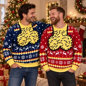 May include: Two long-sleeve crewneck sweaters, one in navy blue and one in red, both featuring a yellow graphic of two rounded, textured shapes on the chest. The sweaters have a yellow collar, cuffs, and hem, with white reindeer and snowflake patterns.