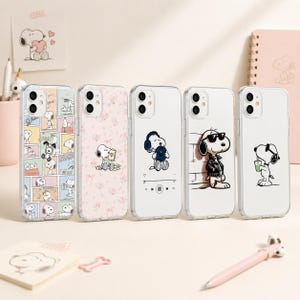 Könnte beinhalten: Fünf transparente Handyhüllen mit Snoopy-Motiven. Die erste zeigt einen Comic-Streifen, die zweite ein rosa Blumenmuster, die dritte Snoopy mit Kopfhörern, die vierte Snoopy in einer Lederjacke und die fünfte Snoopy beim Trinken eines Getränks.