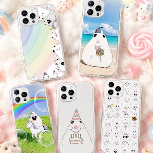 May include: Five clear phone cases featuring cartoon hamster illustrations. Designs include hamsters with rainbows, a hamster on a beach with a lollipop, a hamster riding a unicorn, a hamster with a birthday cake, and a grid of various hamster faces.
