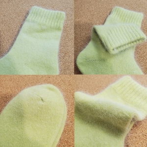 May include: A pair of light lime green socks featuring a soft, fuzzy texture. The socks have a ribbed cuff at the top and a rounded toe section. The material appears to have a fine, brushed finish with visible fibers throughout the fabric.