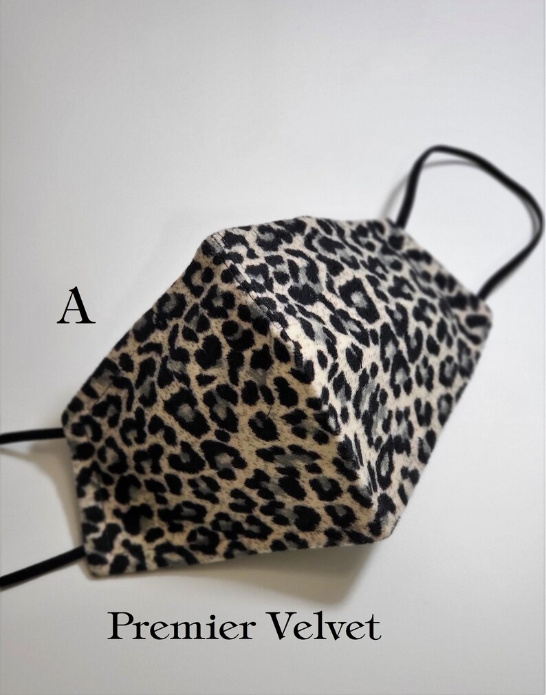 May include: A black and white leopard print face mask made of velvet. The mask has a black elastic band and the text "Premier Velvet" is printed below the mask.