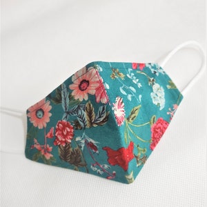 May include: A teal blue face mask with a floral print featuring pink, red, and white flowers. The mask has white elastic ear loops.